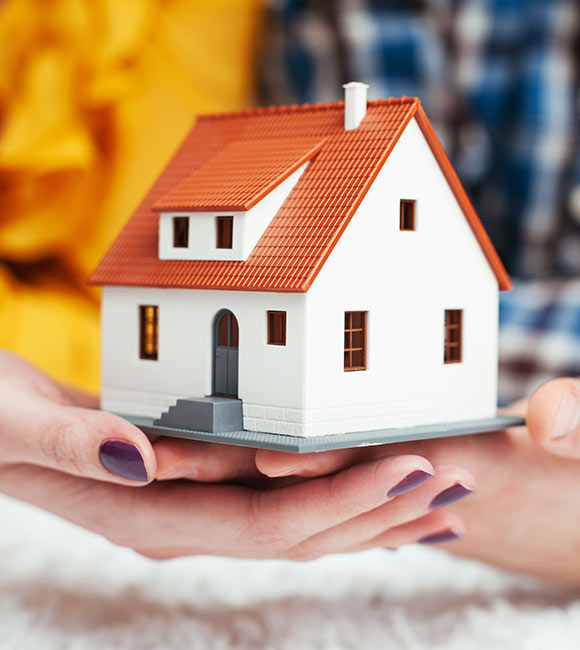 close-up of a man's and woman's hands holding a toy home model